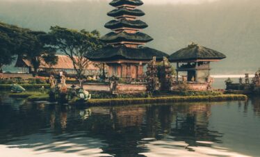 temple beside body of water and trees