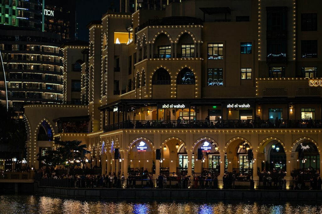 A large building with lights on it next to a body of water
