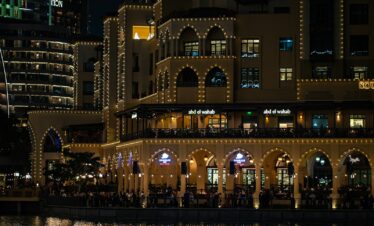 A large building with lights on it next to a body of water