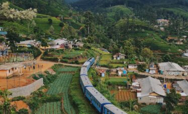 blue train travelling near houses
