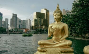 a golden buddha statue sitting in front of a body of water