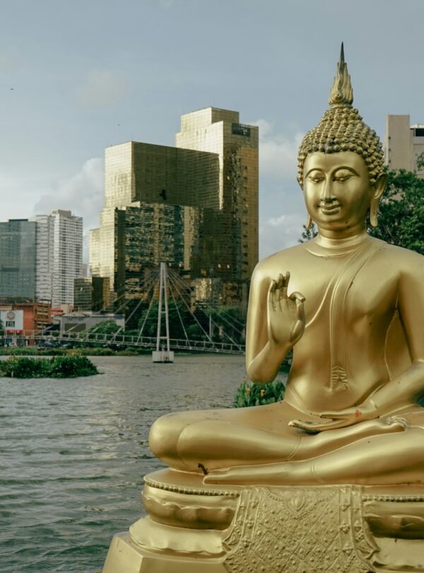 a golden buddha statue sitting in front of a body of water