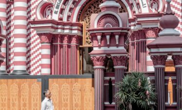 a woman in a white dress walking past a pink and white building