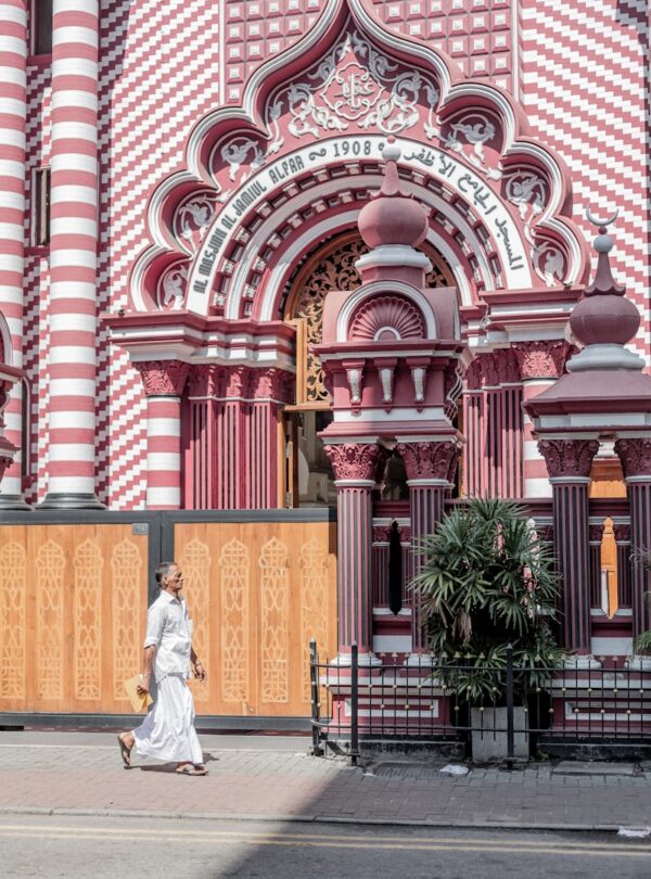 a woman in a white dress walking past a pink and white building