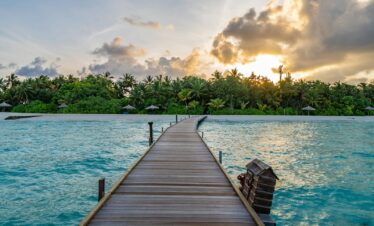 brown wooden dock on blue sea under white clouds during daytime