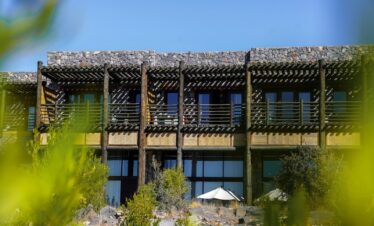a tall building with a balcony and a white umbrella in front of it