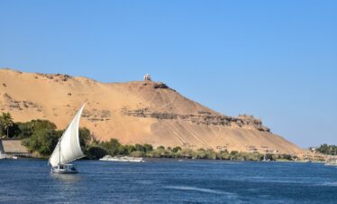 a sailboat in a body of water with a mountain in the background