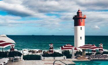 red and white lighthouse near body of water during daytime