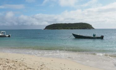 a boat on the beach with a small island in the background