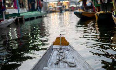 a boat floating down a river next to a bunch of buildings