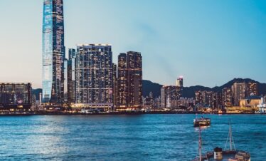 white and brown boat on sea near city buildings during daytime