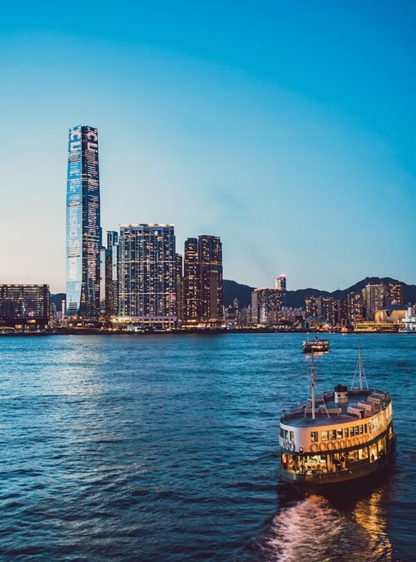 white and brown boat on sea near city buildings during daytime