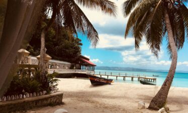 brown wooden boat on white sand near body of water during daytime