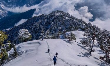 person in black jacket and black pants standing on snow covered mountain during daytime