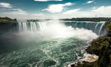 water falls under blue sky during daytime