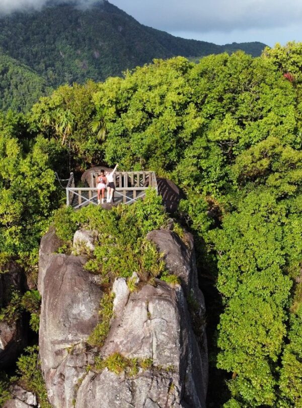 a couple of people standing on top of a wooden bridge