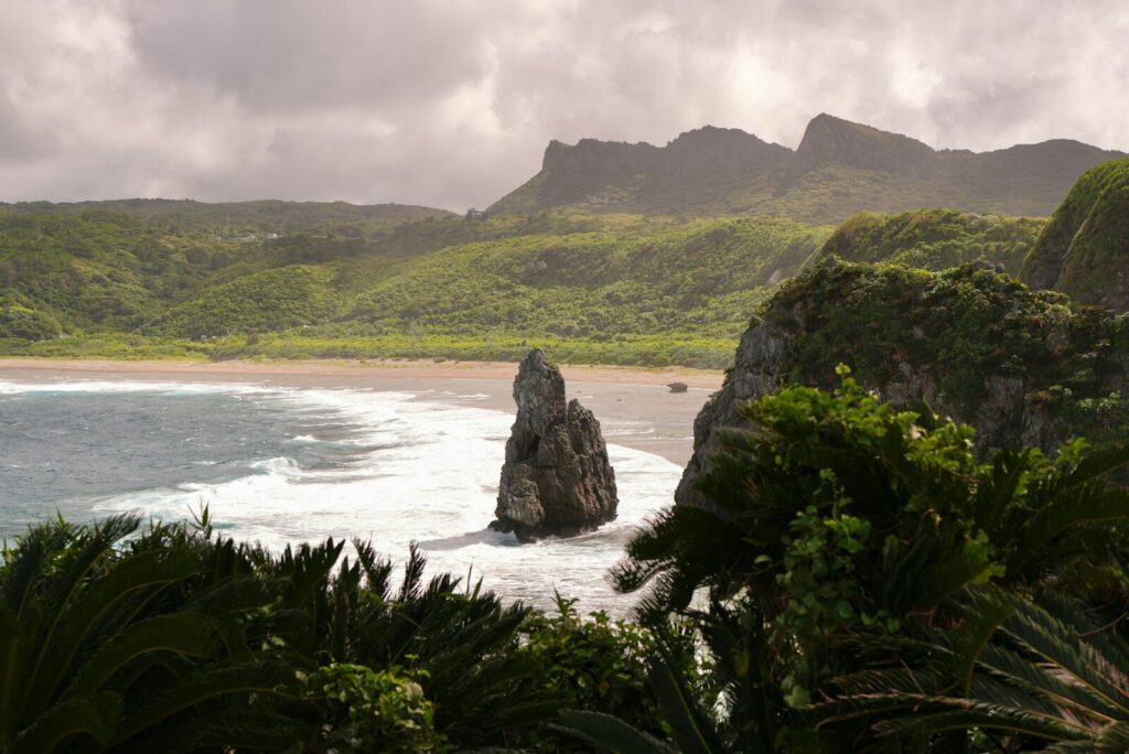 Rocky outcrop in a tropical bay with lush green hills