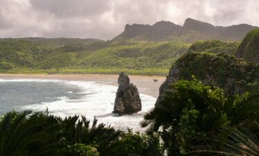 Rocky outcrop in a tropical bay with lush green hills