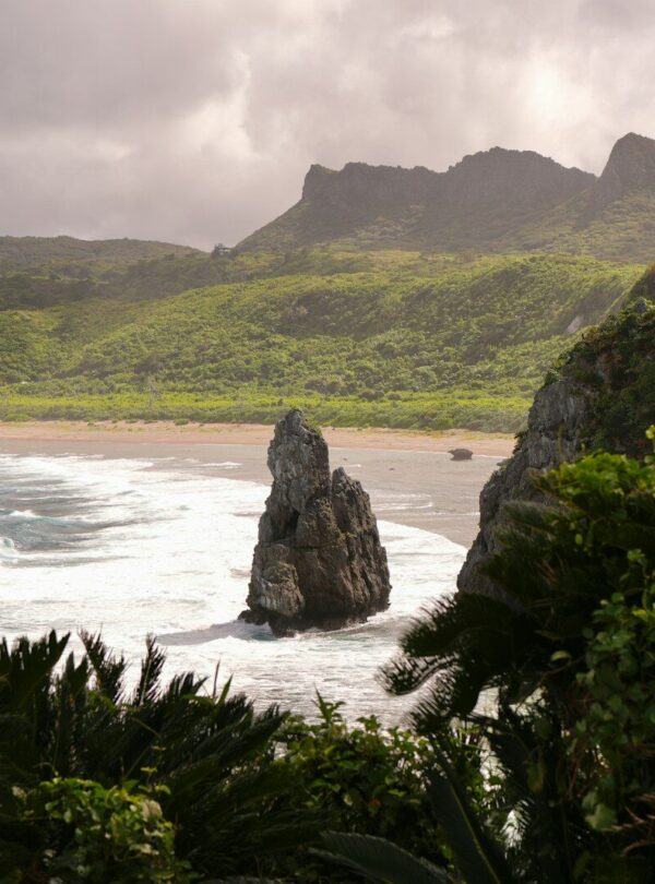 Rocky outcrop in a tropical bay with lush green hills