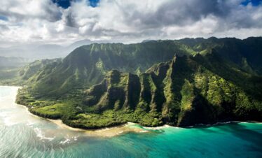 aerial photography of green mountain beside body of water under white sky