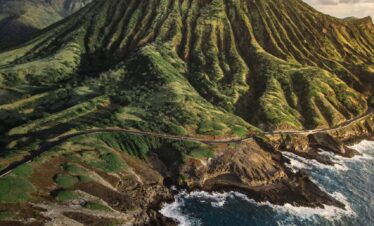 green mountain beside body of water during daytime