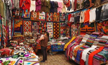 woman in store with display of assorted shirts and textiles