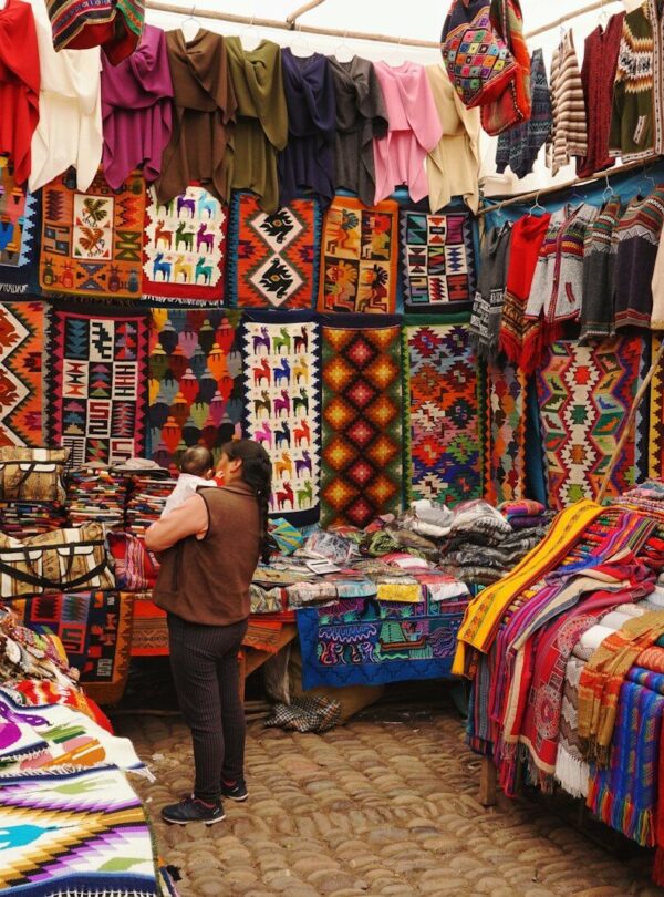 woman in store with display of assorted shirts and textiles
