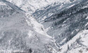 black bridge surrounded by mountain covered with snow under white sky
