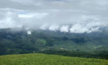a lush green hillside covered in clouds and grass