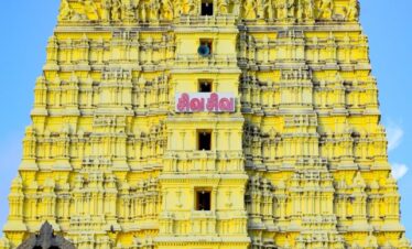 a very tall yellow building with statues on it