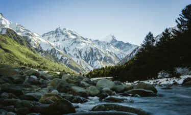 rocky river with snow covered mountains in the distance