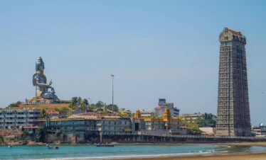 a tall tower with a statue on top of it next to a body of water